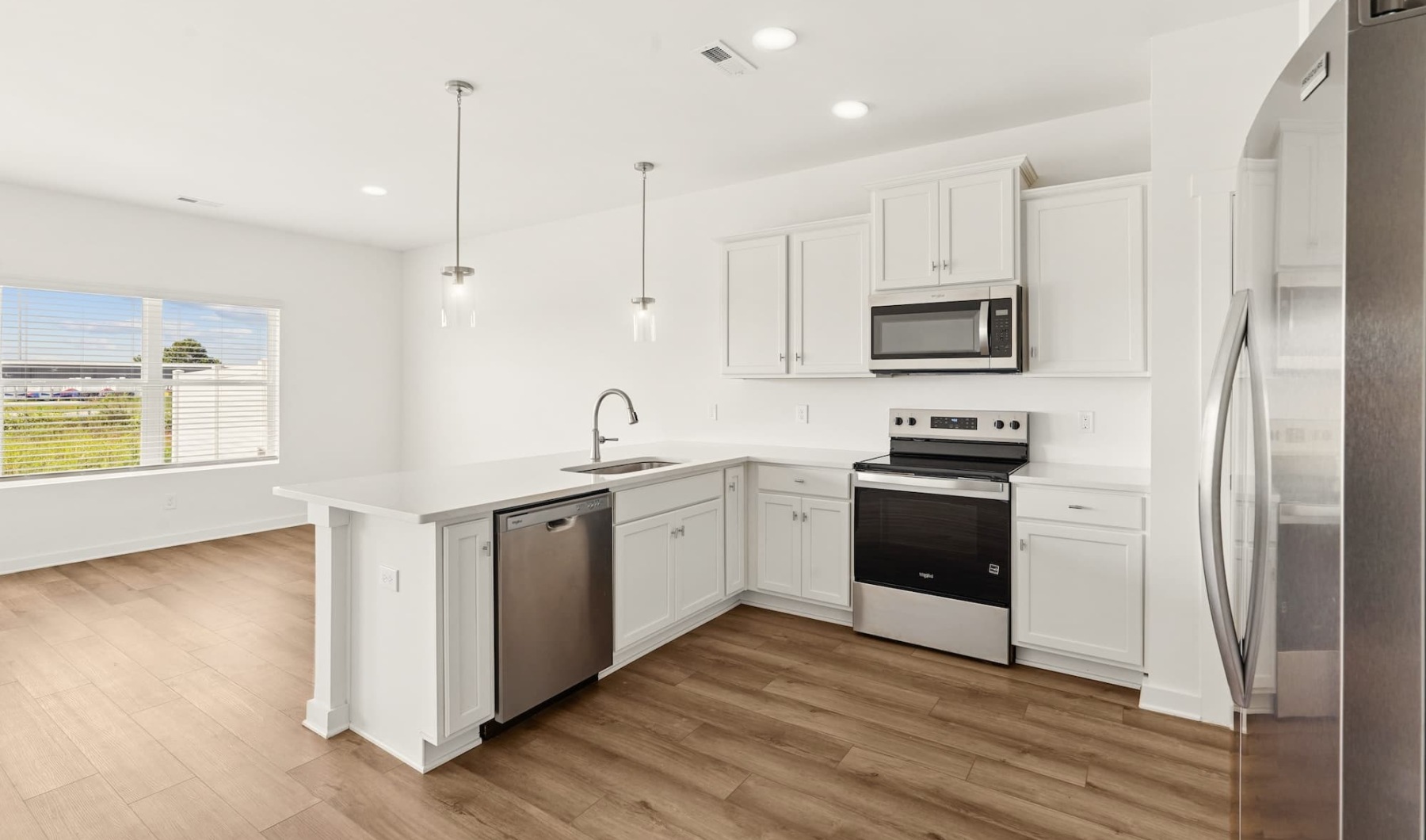 a living room and kitchen with white cabinets