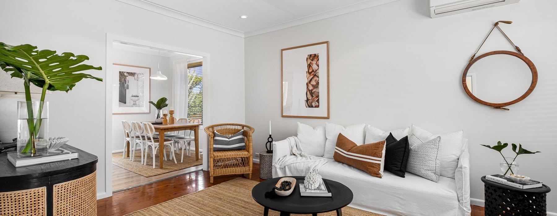 a living room with a white couch and a round mirror